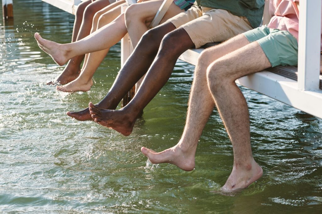 Barefoot multiracial friends in casualwear splashing water